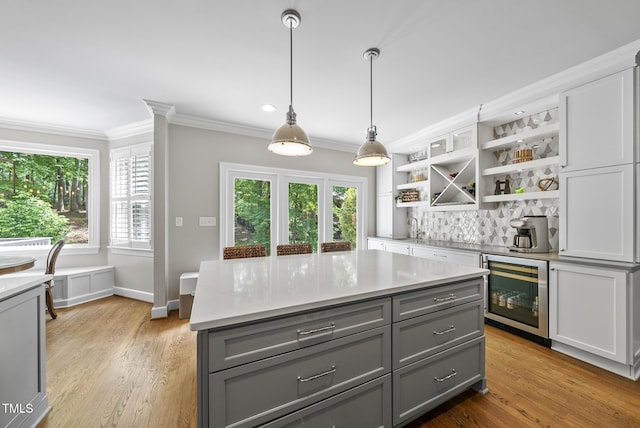 kitchen with beverage cooler, open shelves, gray cabinetry, and ornamental molding