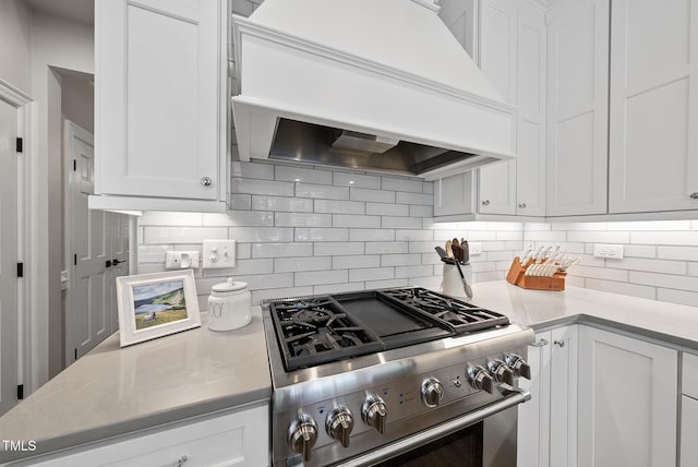 kitchen featuring white cabinetry, decorative backsplash, premium range hood, and stainless steel gas stove