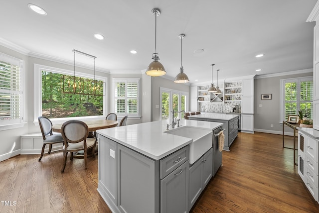 kitchen featuring crown molding, a sink, gray cabinets, recessed lighting, and a center island with sink