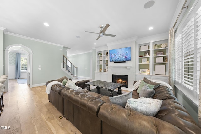 living room featuring crown molding, a fireplace, a ceiling fan, baseboards, and recessed lighting