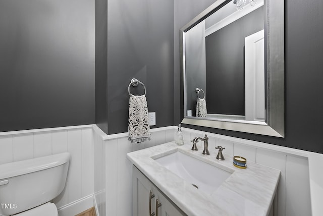 bathroom featuring vanity, wainscoting, and toilet