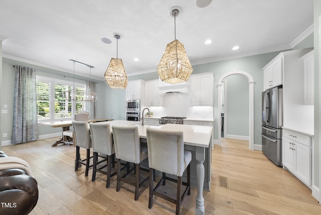 kitchen with light countertops, a chandelier, appliances with stainless steel finishes, and ornamental molding