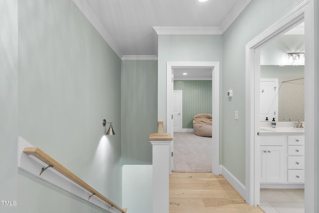 corridor featuring crown molding, light wood finished floors, and an upstairs landing