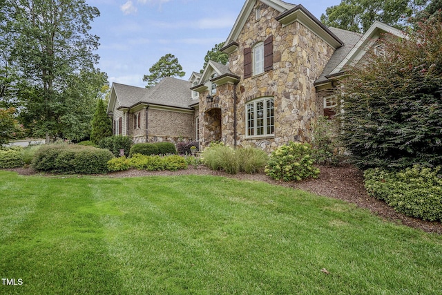 1605 Hunting Ridge Rd, Raleigh, NC 27615 - french country home featuring a shingled roof, a front lawn, and stone siding