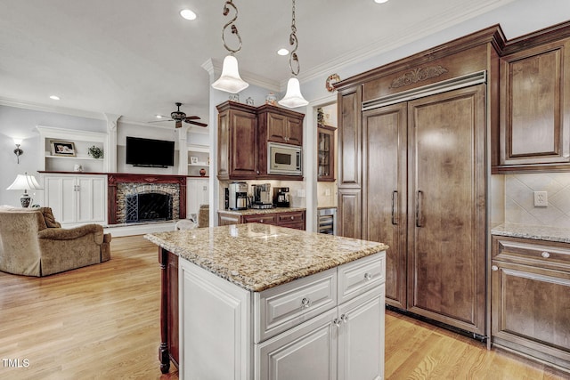 1605 Hunting Ridge Rd, Raleigh, NC 27615 - kitchen featuring built in appliances, a kitchen island, open floor plan, light wood-type flooring, and a ceiling fan