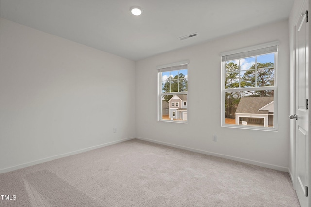 spare room with baseboards and light colored carpet