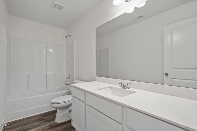 bathroom with toilet, wood finished floors, vanity, and bathing tub / shower combination