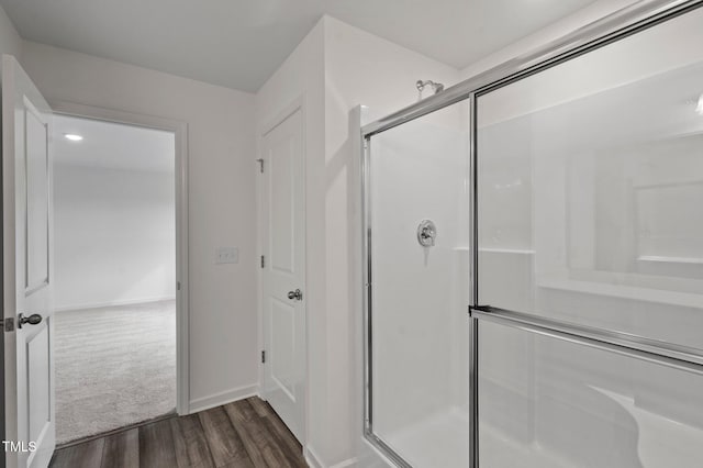 bathroom featuring wood finished floors, a stall shower, and baseboards