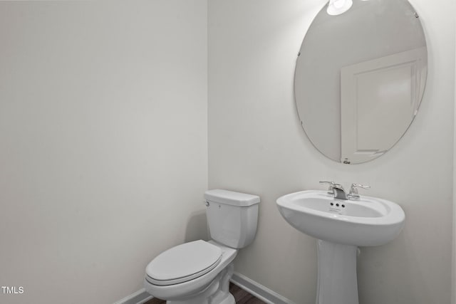 bathroom featuring toilet, baseboards, and wood finished floors