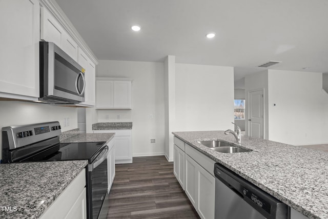 kitchen featuring appliances with stainless steel finishes, a sink, white cabinetry, light stone countertops, and recessed lighting