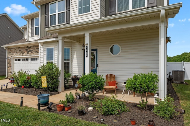view of front of property featuring fence, covered porch, central AC unit, and an attached garage
