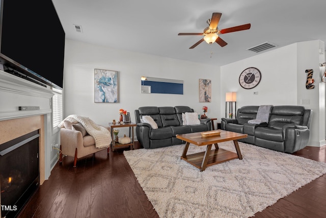 living room with a ceiling fan, visible vents, wood finished floors, and a fireplace
