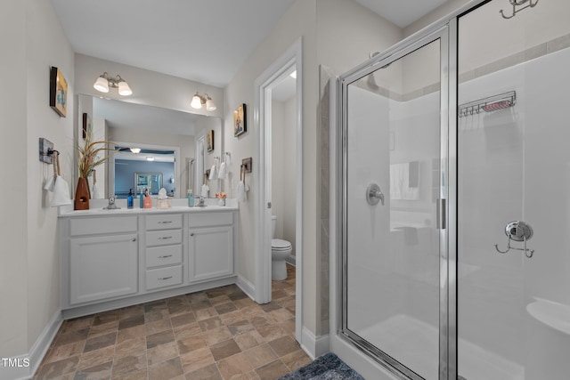 bathroom with stone finish flooring, toilet, a stall shower, and a sink
