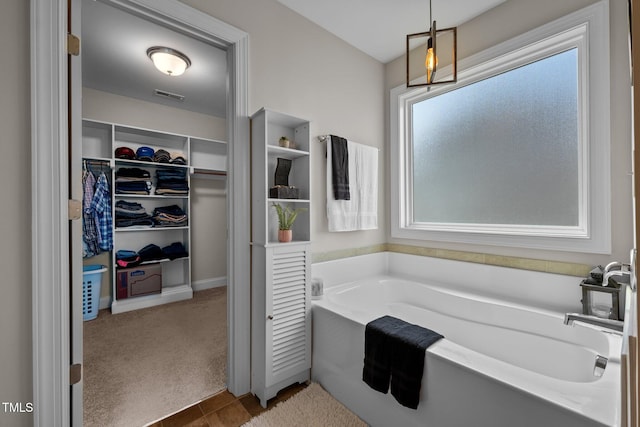 full bath with a bath, a walk in closet, and visible vents