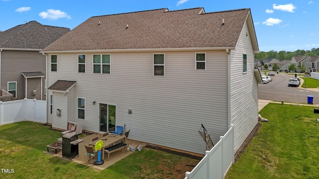rear view of house with a lawn, a shingled roof, a fenced backyard, and a patio area