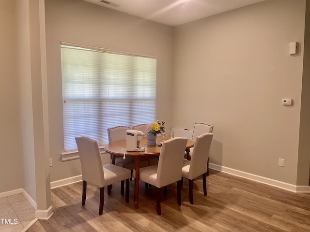 dining space with light wood-style floors, baseboards, and visible vents