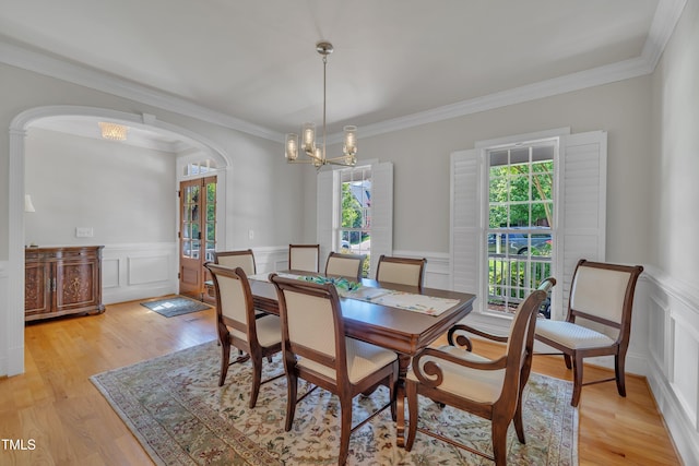dining space featuring a decorative wall, light wood-type flooring, and a chandelier