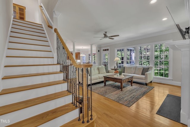 living area featuring crown molding, ceiling fan, plenty of natural light, and stairs