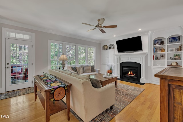 living area with ceiling fan, a fireplace with flush hearth, ornamental molding, and light wood-style floors