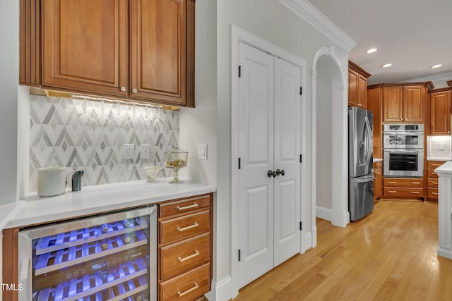 bar with a dry bar, stainless steel appliances, decorative backsplash, light wood-type flooring, and wine cooler