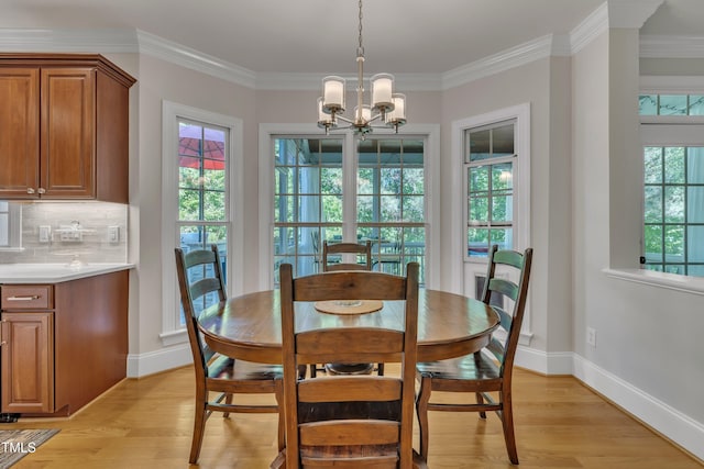 dining room featuring an inviting chandelier, baseboards, ornamental molding, and light wood-type flooring