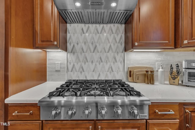 kitchen with decorative backsplash, stainless steel gas cooktop, premium range hood, and light countertops
