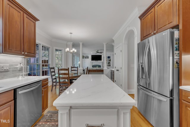 kitchen with crown molding, light wood-style floors, appliances with stainless steel finishes, and tasteful backsplash