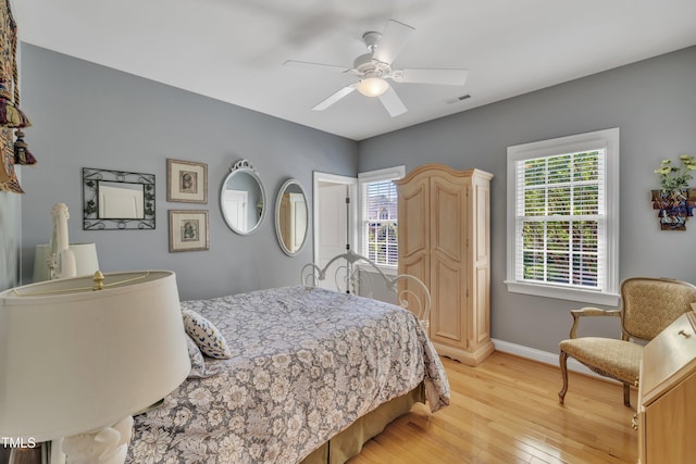 bedroom featuring baseboards, visible vents, ceiling fan, and light wood-style floors