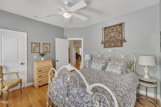 bedroom with baseboards, a ceiling fan, light wood-type flooring, and visible vents