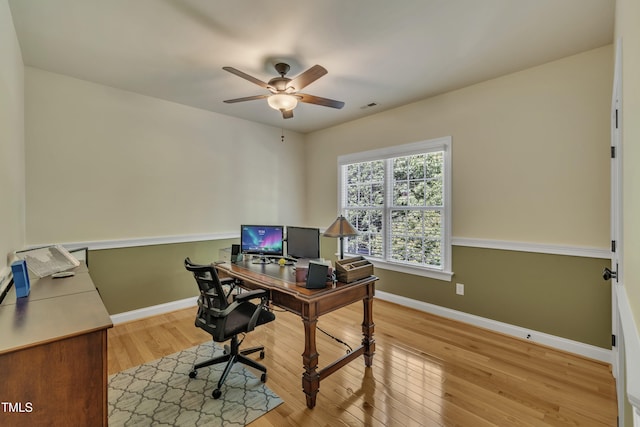 office featuring baseboards, a ceiling fan, wood finished floors, and visible vents