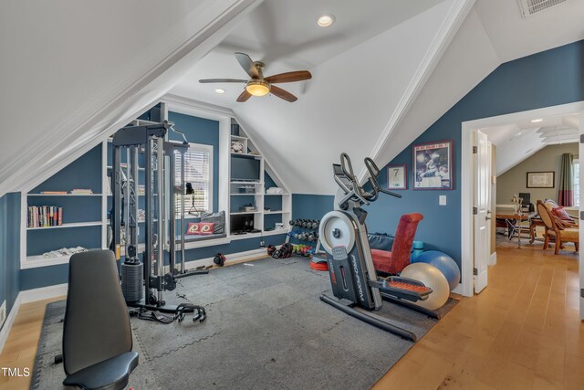 workout room featuring visible vents, built in features, wood finished floors, a ceiling fan, and vaulted ceiling