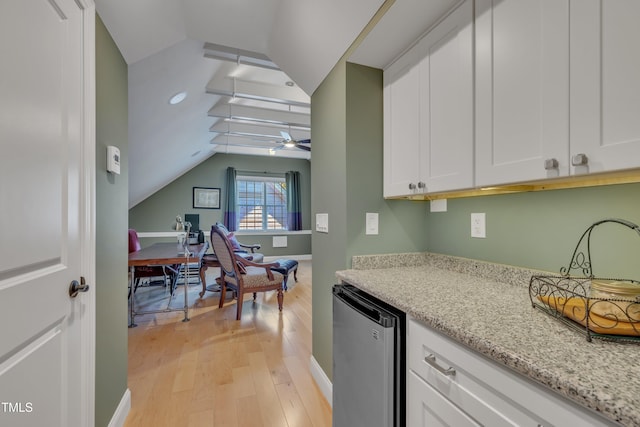 kitchen with light wood-type flooring, white cabinetry, vaulted ceiling, and refrigerator