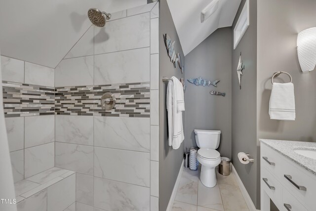 bathroom featuring vanity, marble finish floor, lofted ceiling, toilet, and tiled shower