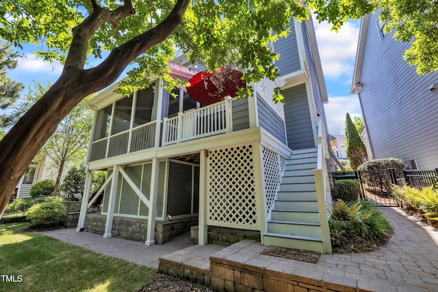 rear view of property featuring a sunroom, fence, stone siding, and stairway