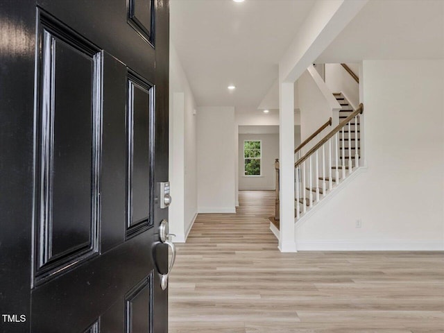 foyer featuring baseboards, recessed lighting, stairs, and light wood finished floors