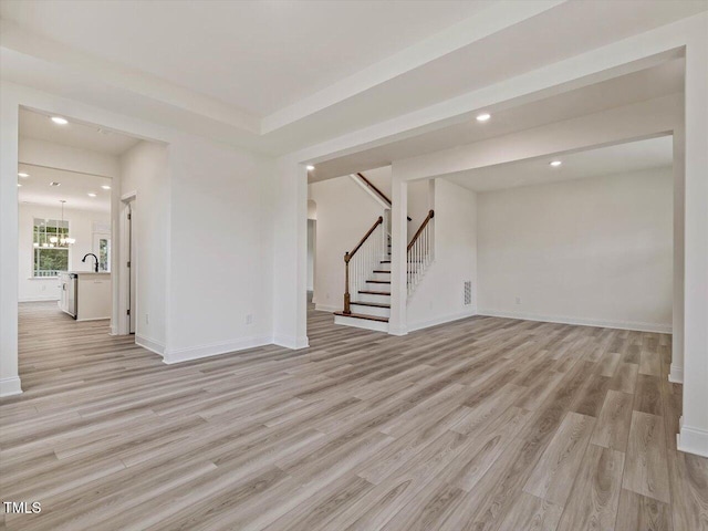 unfurnished living room featuring recessed lighting, stairs, a sink, baseboards, and light wood-type flooring