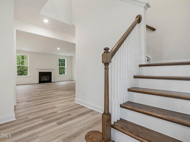 staircase with baseboards, recessed lighting, wood finished floors, and a fireplace