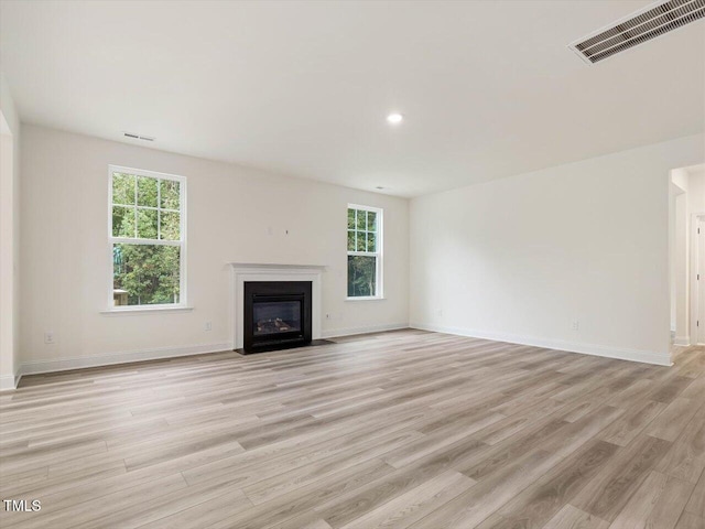 unfurnished living room with light wood finished floors, visible vents, and a healthy amount of sunlight