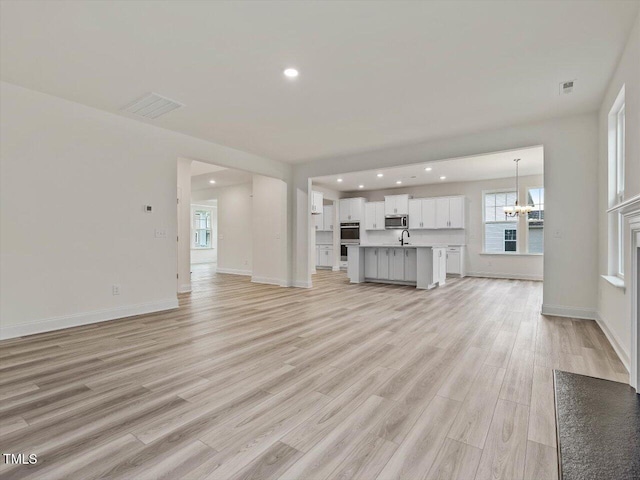 unfurnished living room featuring light wood finished floors, recessed lighting, and an inviting chandelier