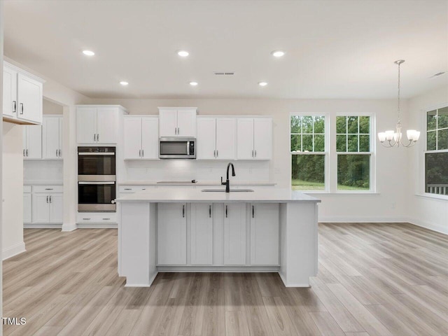 kitchen with light countertops, stainless steel appliances, light wood-type flooring, and a sink