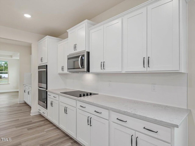 kitchen with white cabinetry, tasteful backsplash, light wood-style flooring, stainless steel appliances, and baseboards