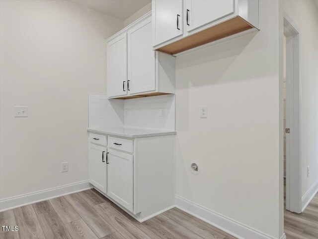 laundry room featuring light wood finished floors and baseboards
