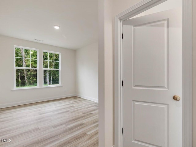 empty room with light wood-style floors, recessed lighting, visible vents, and baseboards
