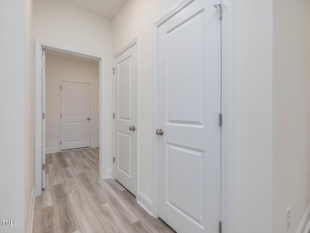 corridor with light wood-style flooring and baseboards