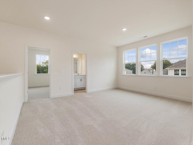 empty room with light colored carpet, recessed lighting, and baseboards