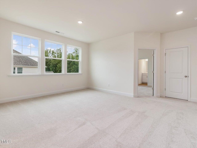 spare room featuring light colored carpet, visible vents, recessed lighting, and baseboards