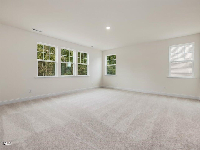 spare room featuring visible vents, light carpet, and baseboards