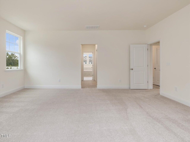 empty room featuring baseboards, visible vents, and light colored carpet