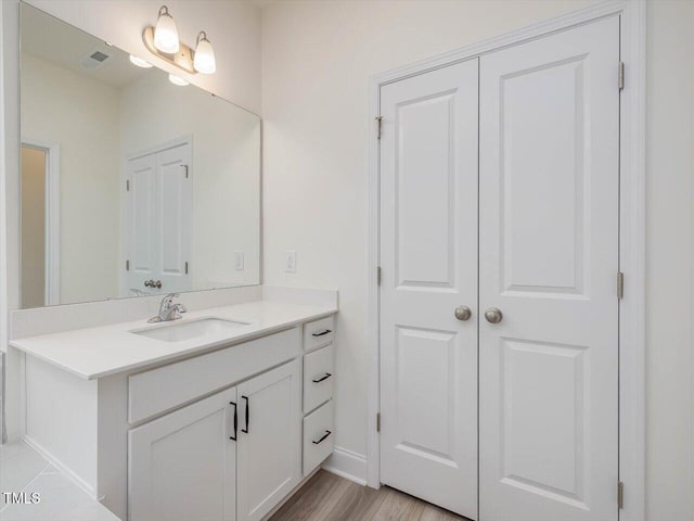 bathroom with wood finished floors, visible vents, vanity, and baseboards