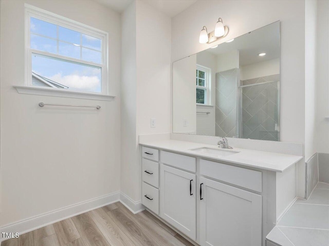 full bathroom featuring baseboards, a stall shower, wood finished floors, and vanity